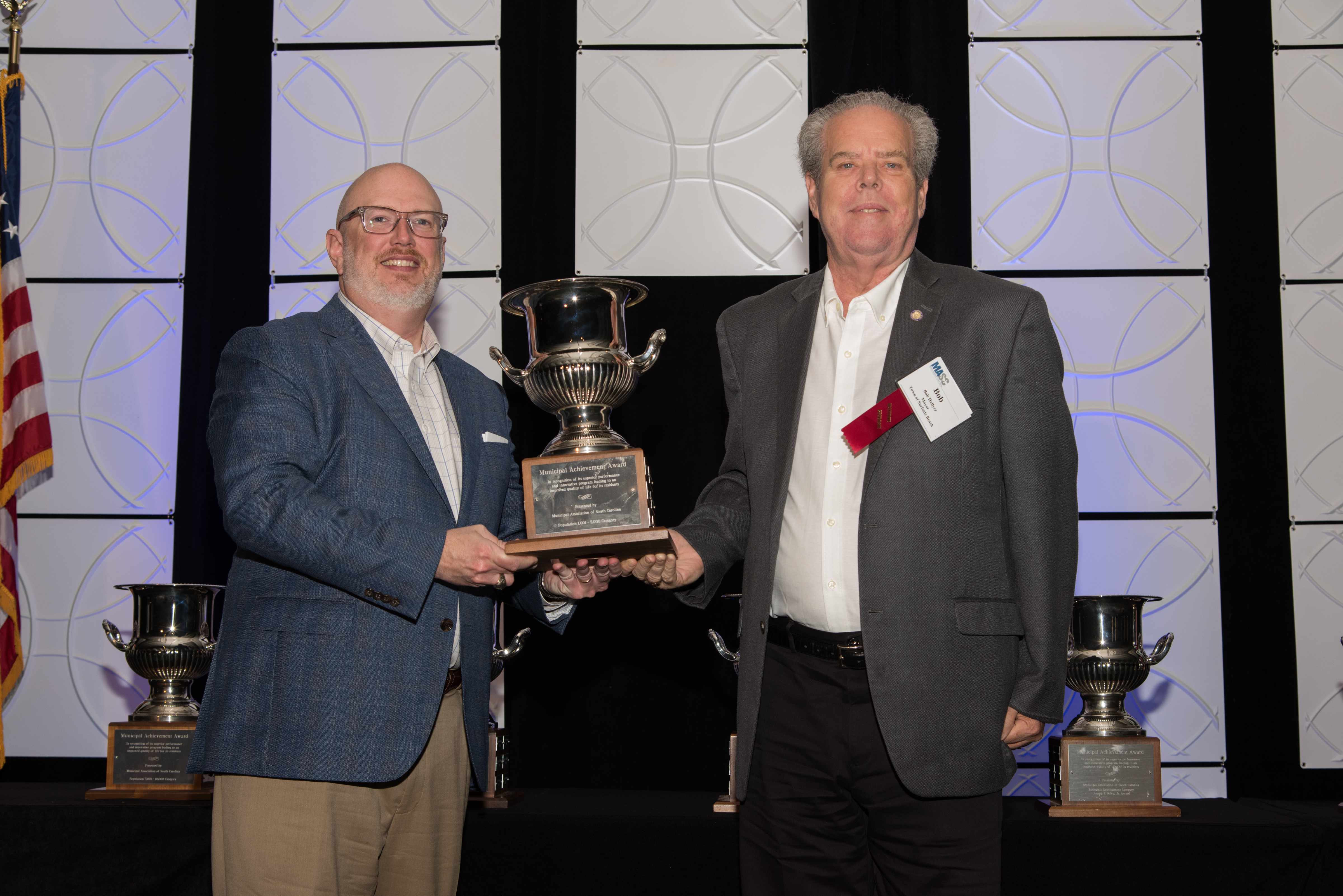 Municipal Association Executive Director Todd Glover, left, presents an Achievement Award trophy for Population 1,001 — 5,000 Ca