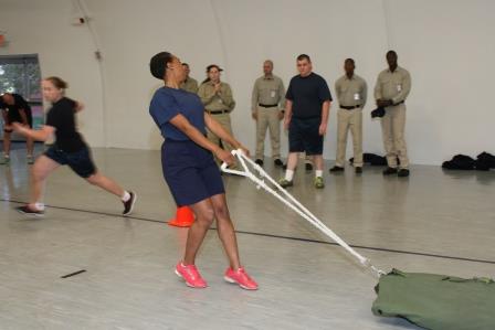A police recruit drags a 150-pound weight during obstacle course